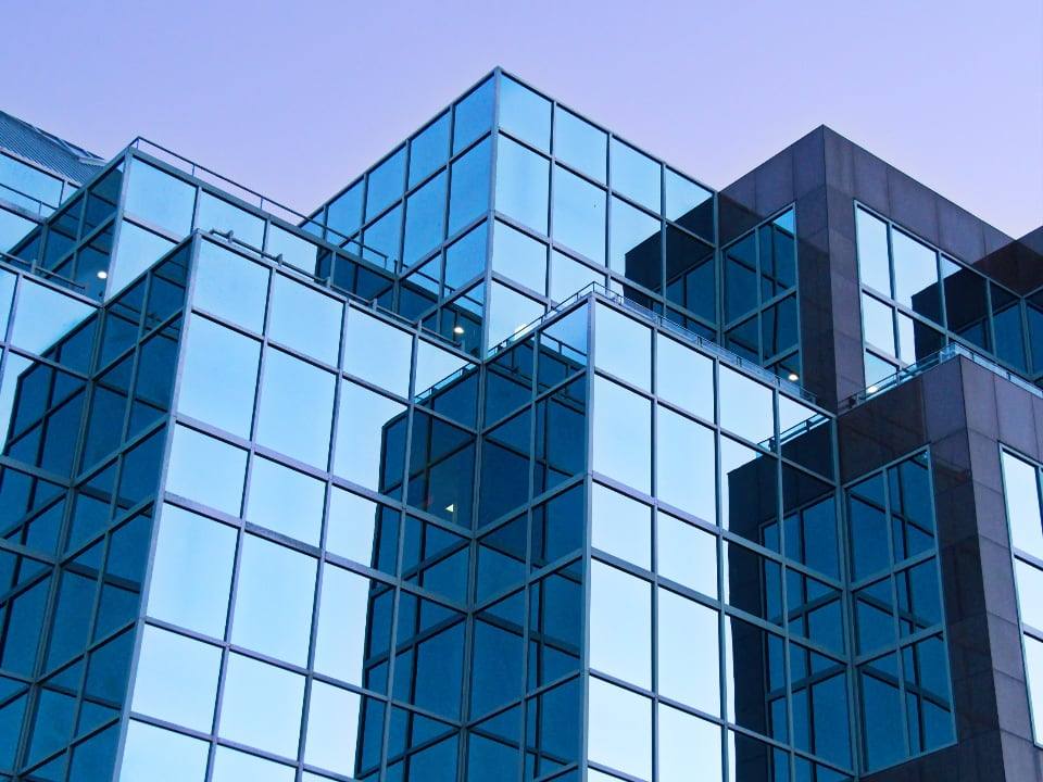 Glass facade of an office building against an evening sky