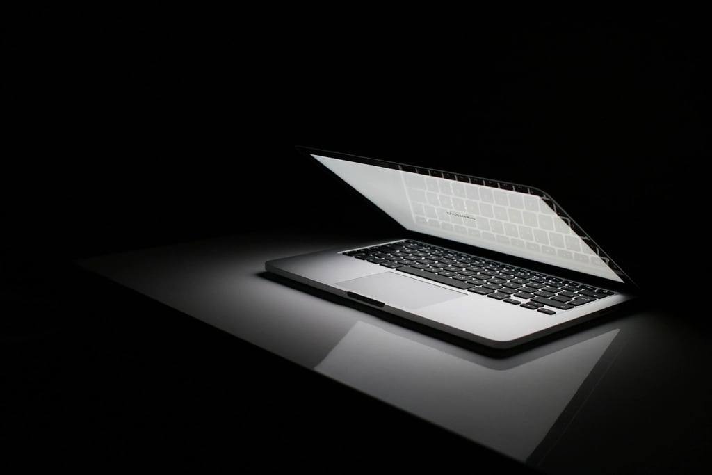 An open laptop glowing in a dark room