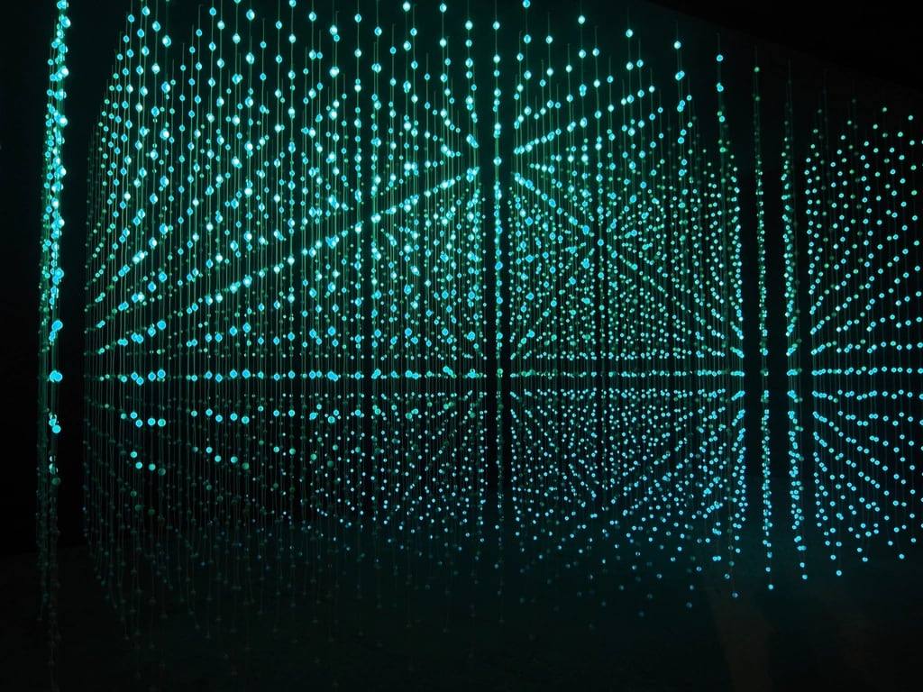 A grid of suspended lights glowing teal in the dark