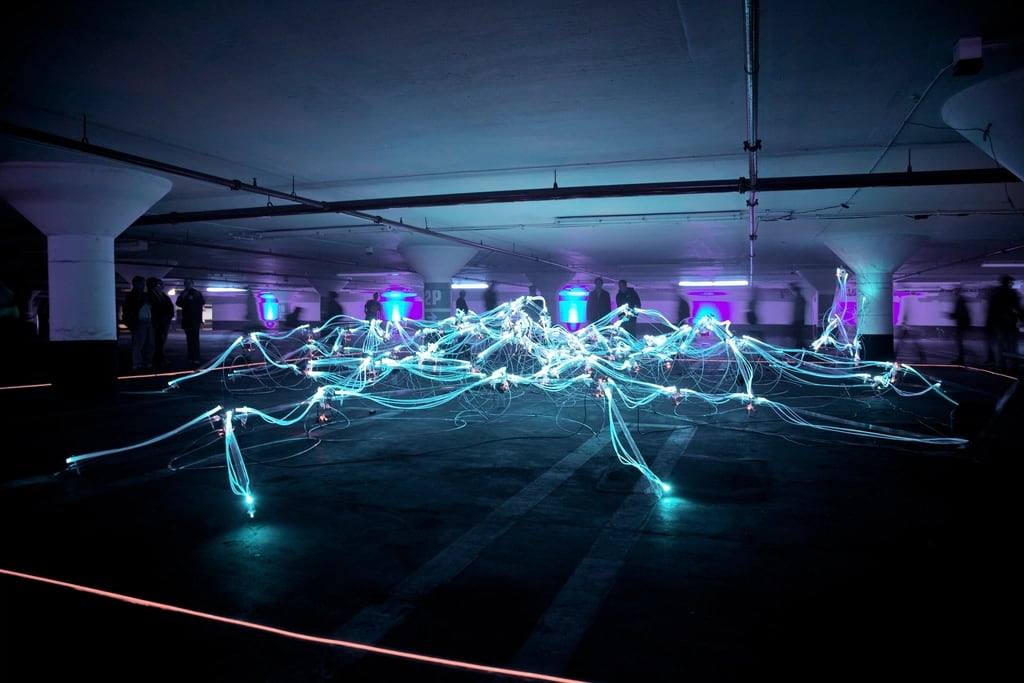 Strands of fibre-optic light spread across a dark car park